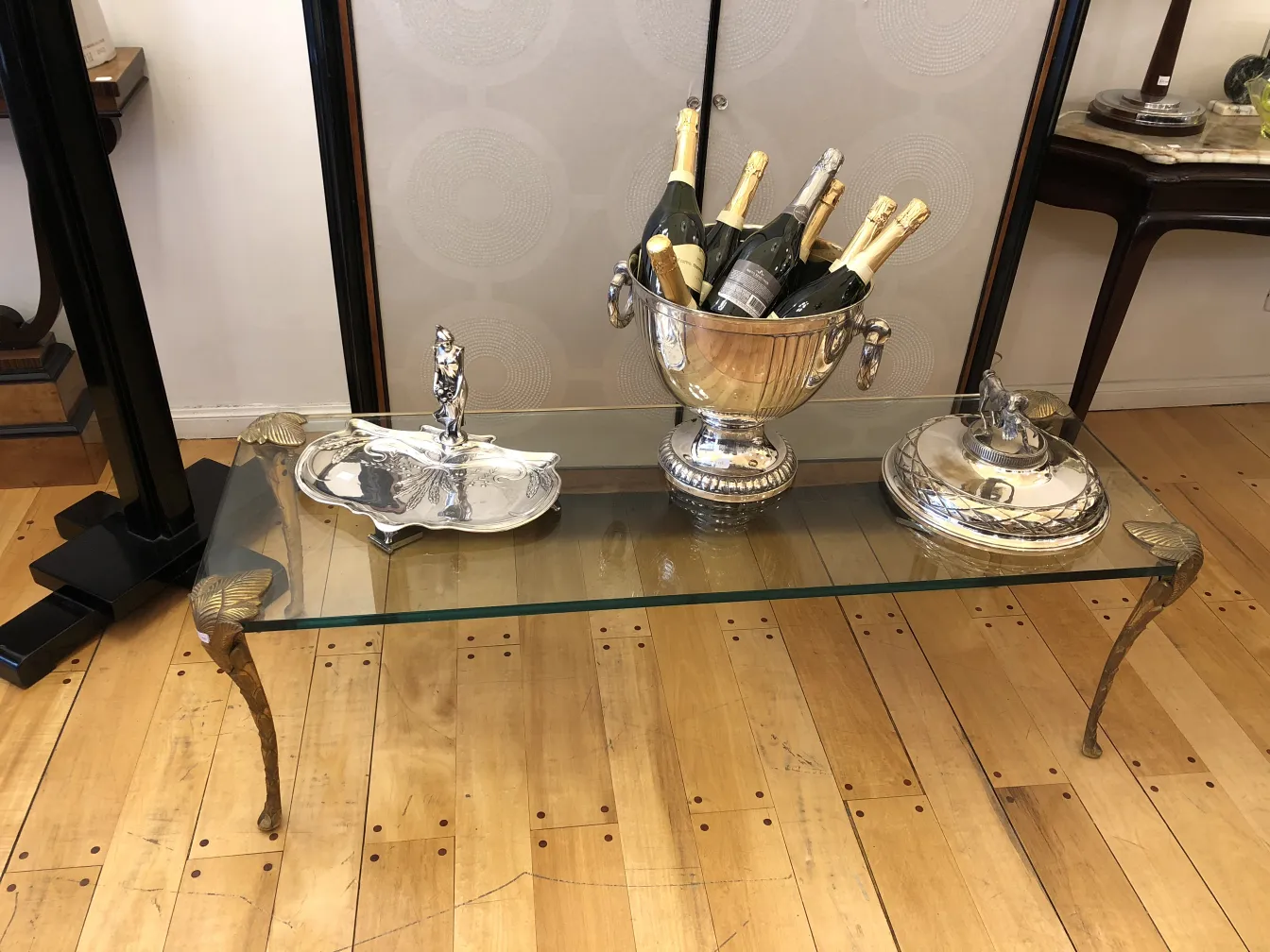 Maison Charles의 앤티크 커피 테이블에 나무 바닥 위에 트레이, 샴페인 버킷 및 장식 액세서리가 있습니다.