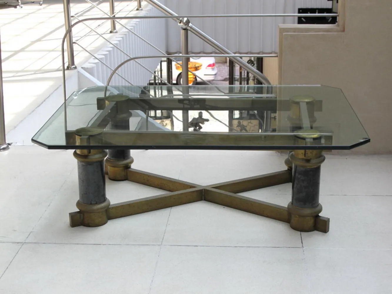 Mesa de centro antiga com tampo de vidro e pernas decorativas em um ambiente moderno.