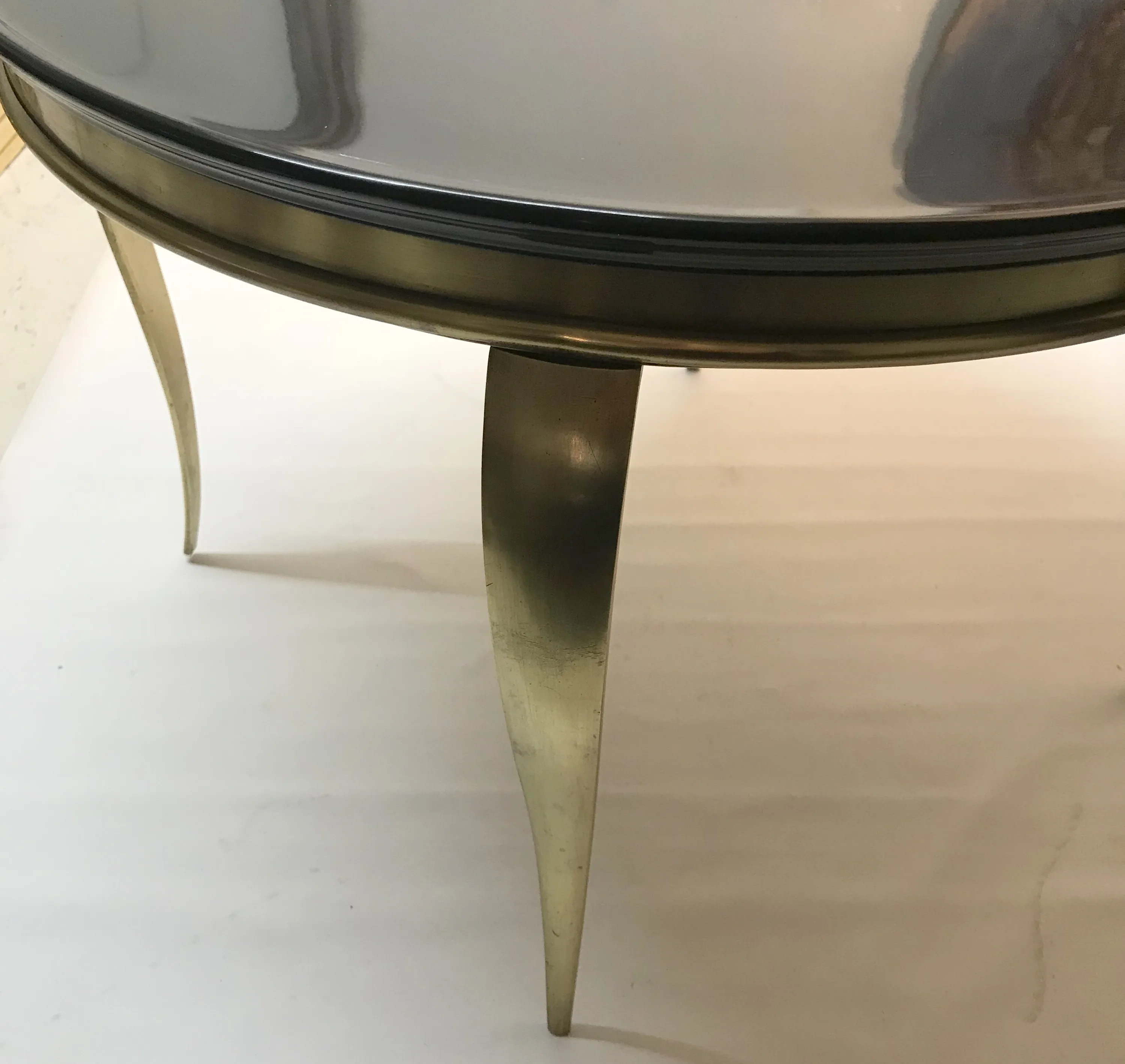 Mesa de centro antiga com pernas douradas e superfície lisa, em um ambiente claro.