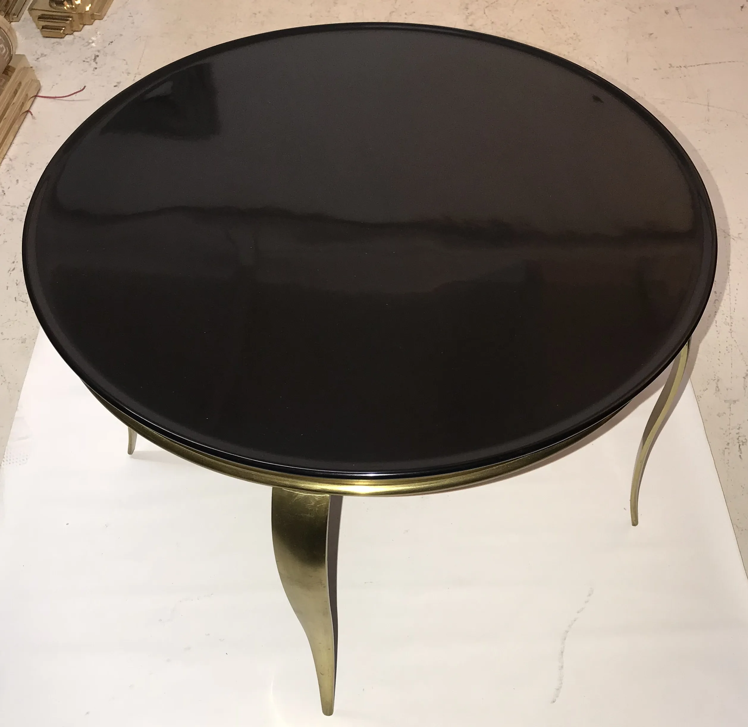 round antique coffee table with gold legs in a setting