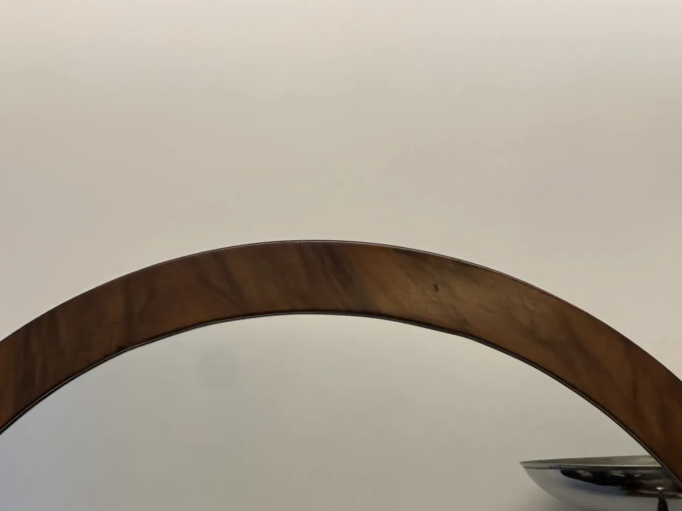 Specchio antico rotondo con bordo decorativo su sfondo neutro.