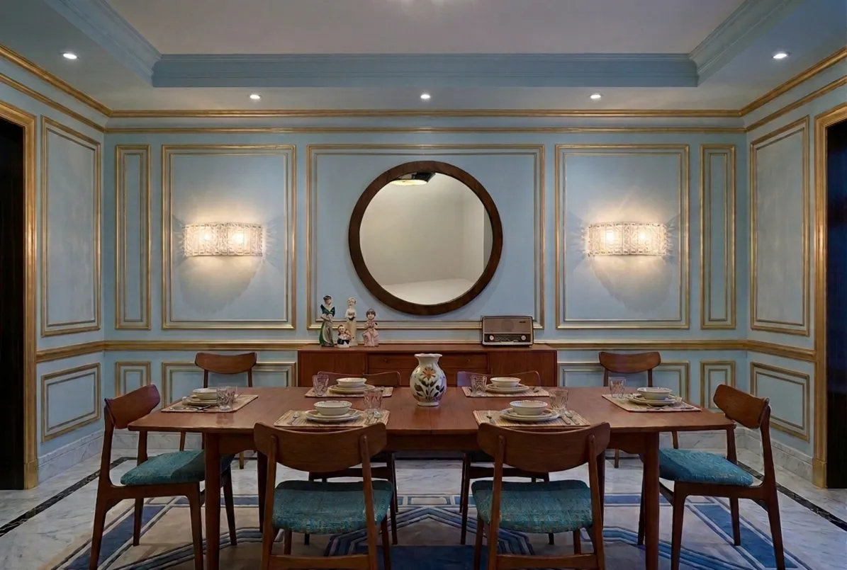 Espejo antiguo redondo sobre un fondo azul con decoración dorada.