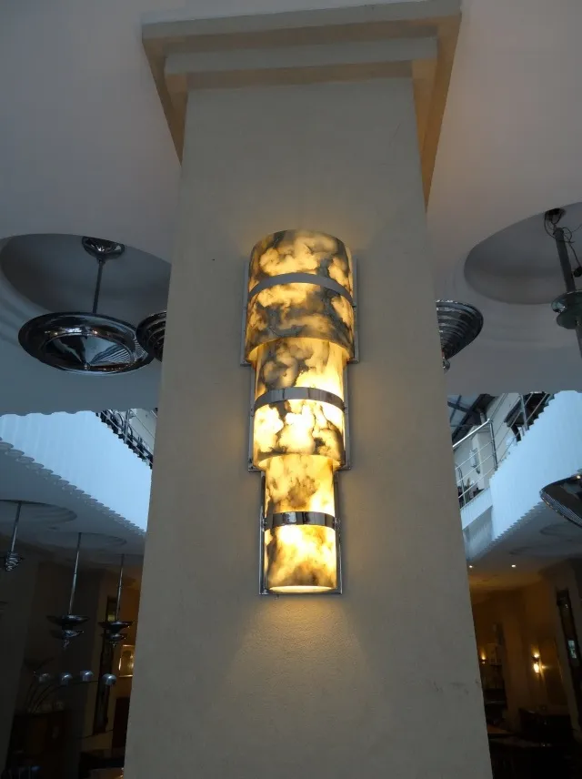 Coppia di applique antiche su una parete illuminata con design decorativo.