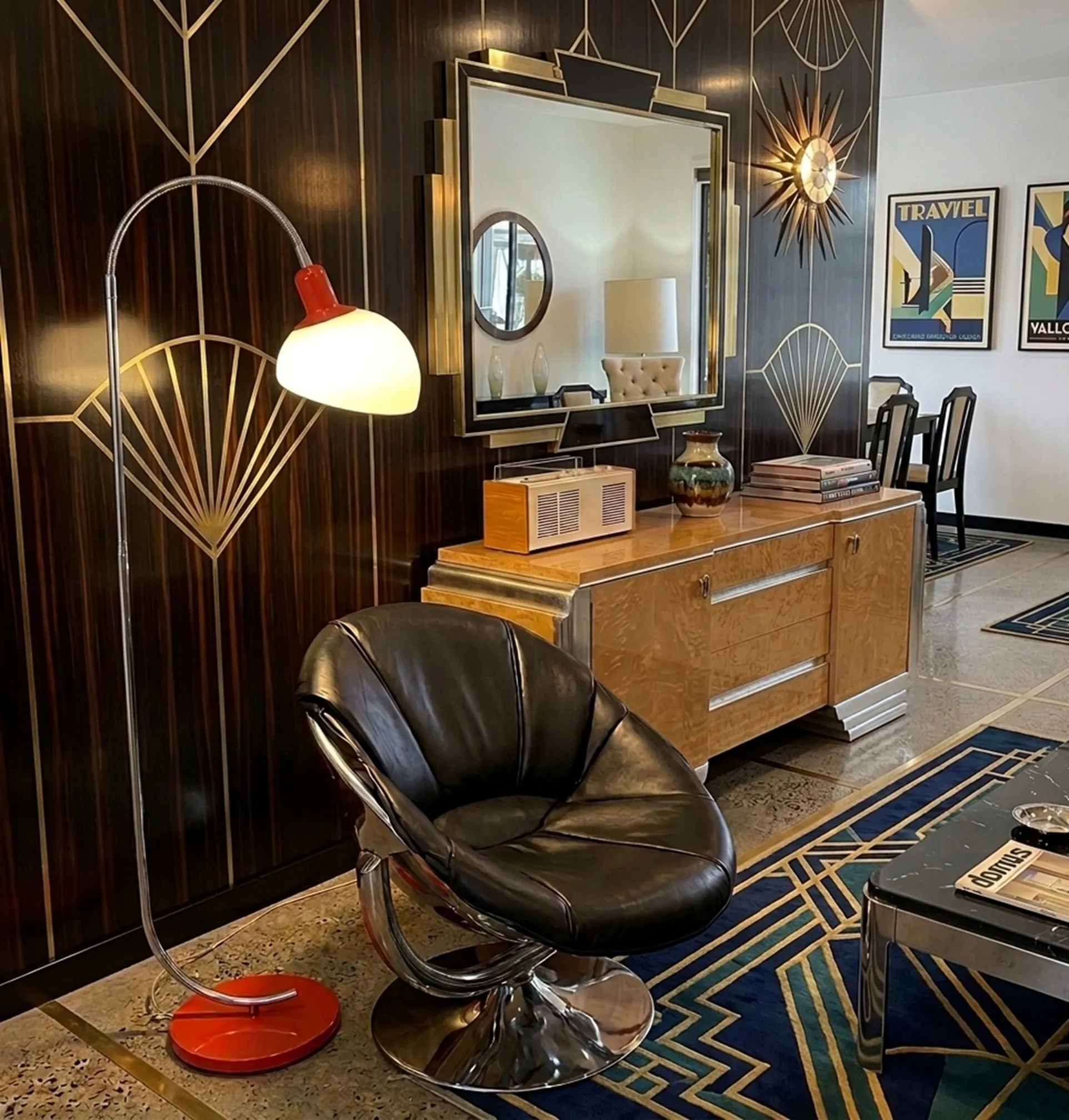 antique floor lamp with a curved shape and warm light, next to a black chair and an elegant furniture piece.