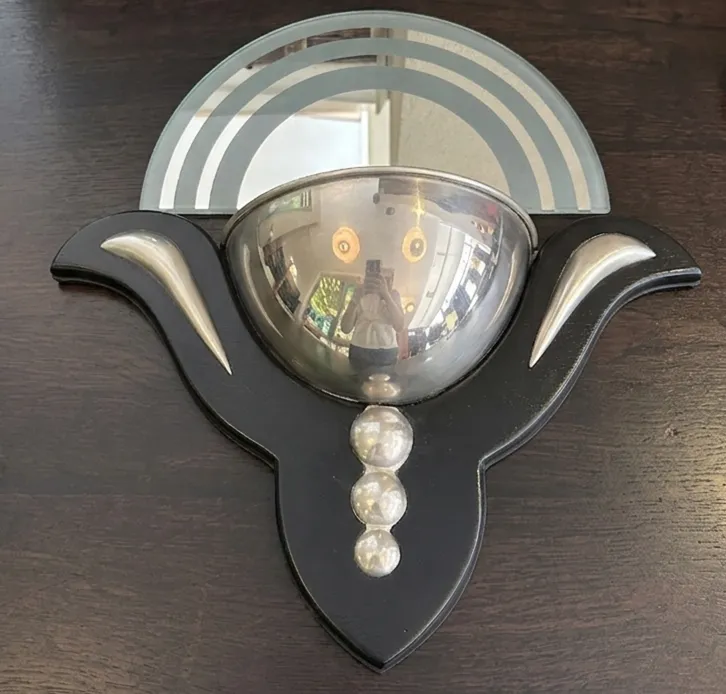 Paire d'appliques anciennes avec une base décorative noire et des éléments réfléchissants dans un cadre chaleureux.