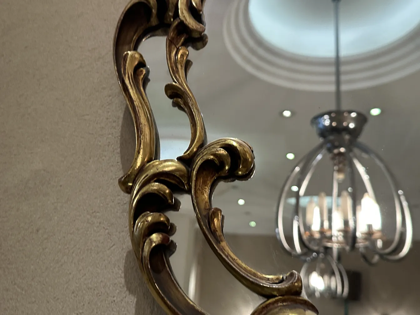 Specchio antico con cornice decorativa e sfondo neutro.