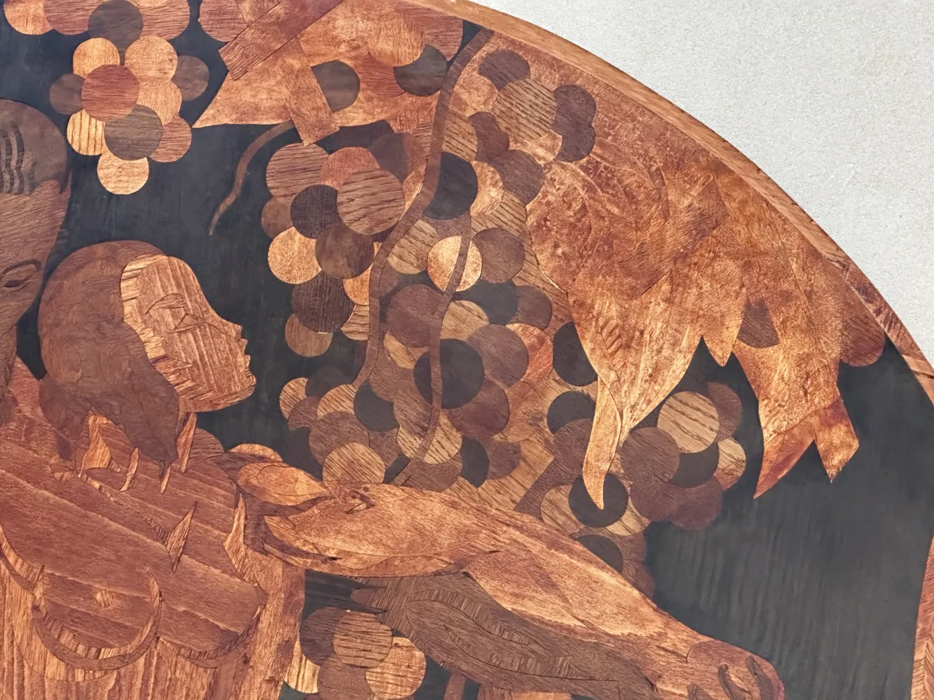 brown detail of antique marquetry featuring human figures and vegetation