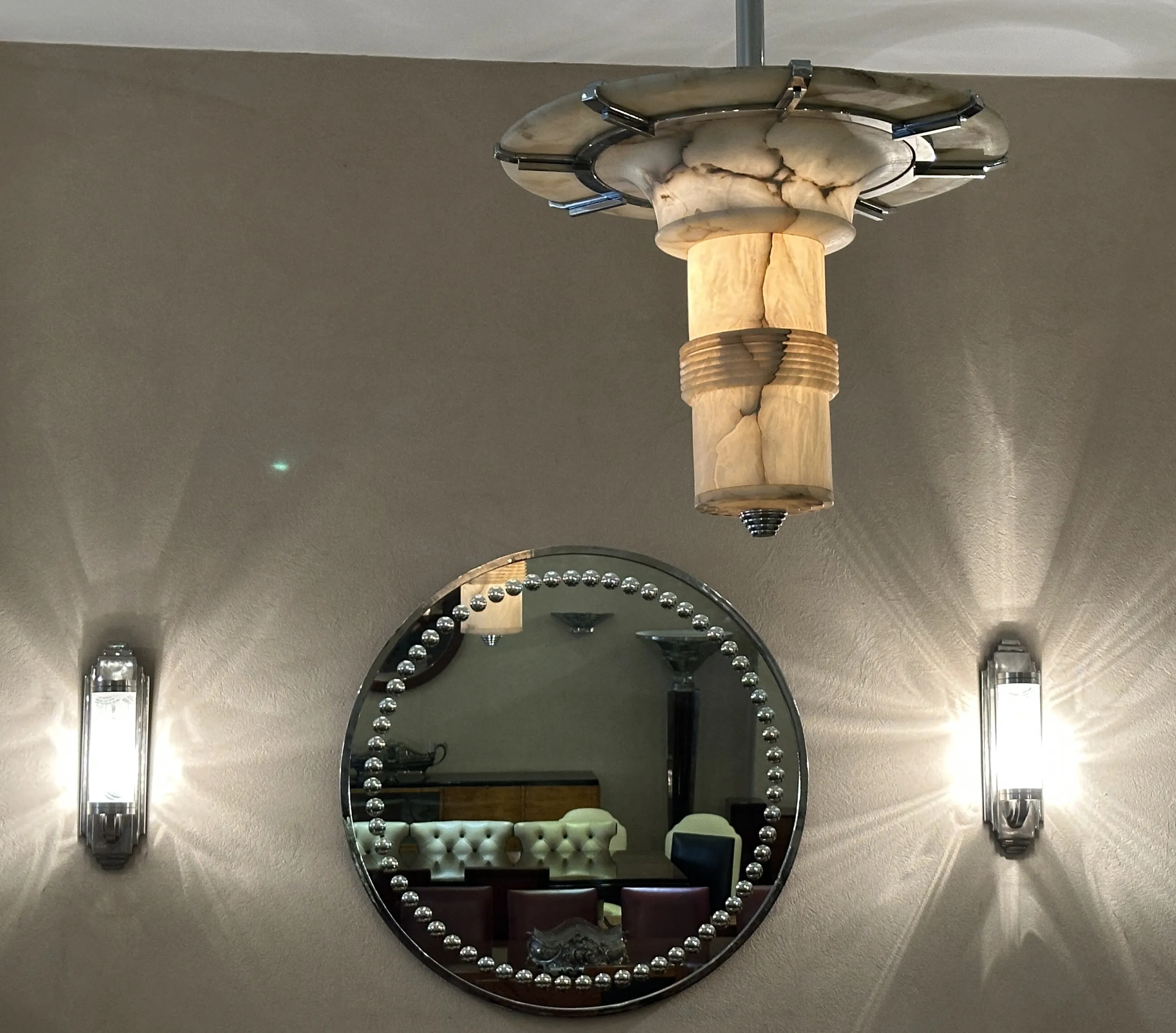 Specchio antico decorativo tondo con lampade ai lati.