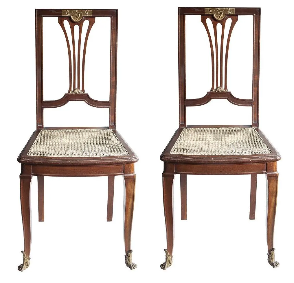 dos sillas antiguas con diseño distintivo y patas elegantes en un ambiente simple