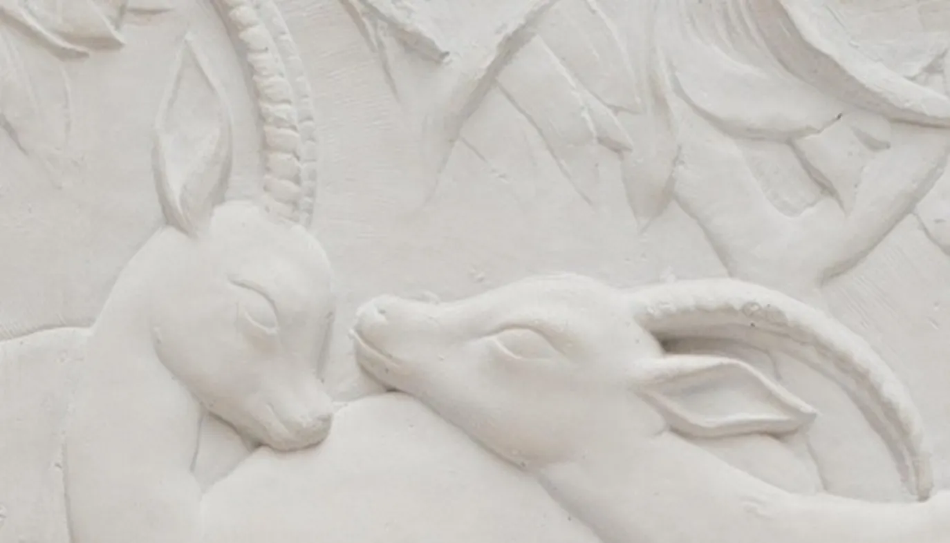 detalle de antigua placa de pared con relieves de animales en blanco