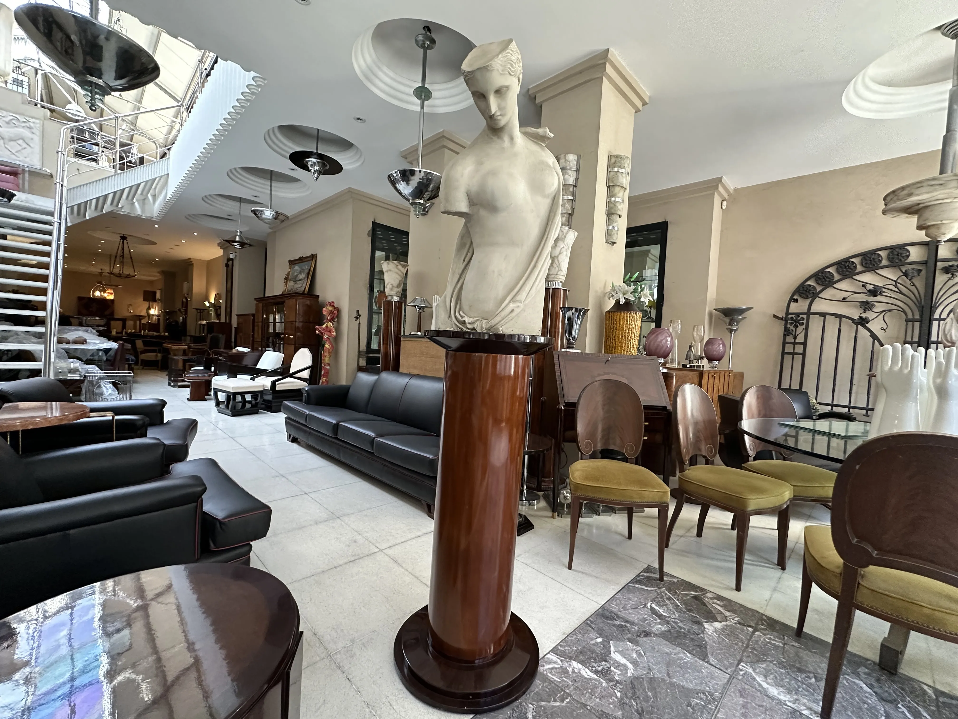 escultura clásica sobre pedestal en una tienda de antigüedades, contemporánea con decoración en tono claro