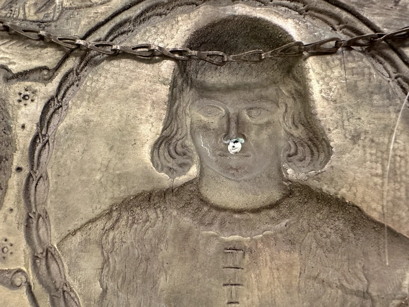 Placa de pared antigua con imagen de Cristóbal Colón, detalles visibles.