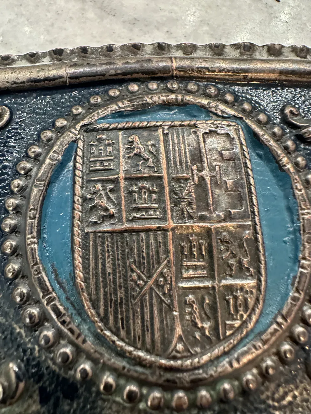 Antique wall plate featuring an ornate shield representing Christopher Columbus, with intricate relief details.