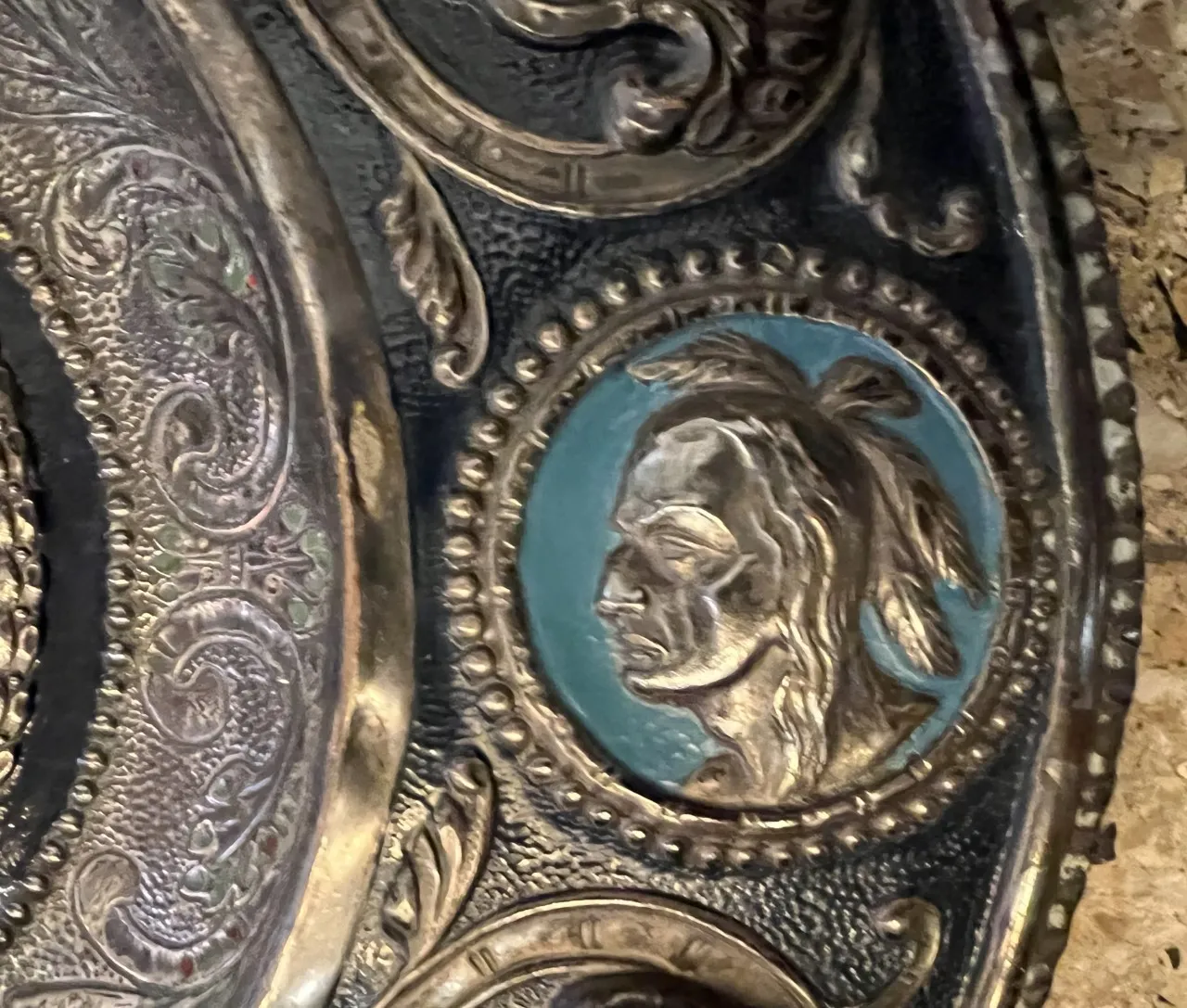 Antique wall plate featuring the face of Cristobal Colon with decorative details in a styled environment.