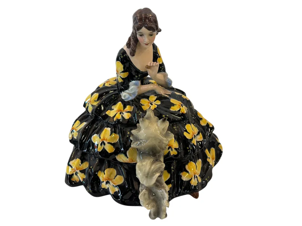 Antica figurina in ceramica di donna con abito nero e fiori gialli.