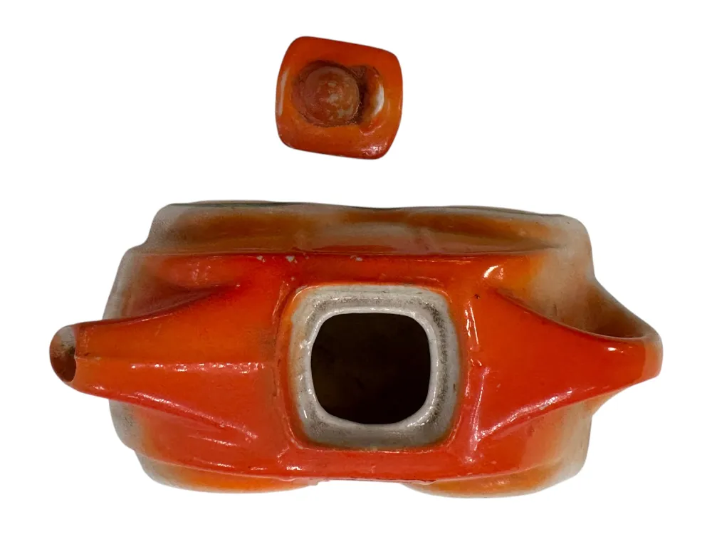 Antiga peça de cerâmica decorativa laranja, com forma distinta, exibida em fundo neutro.