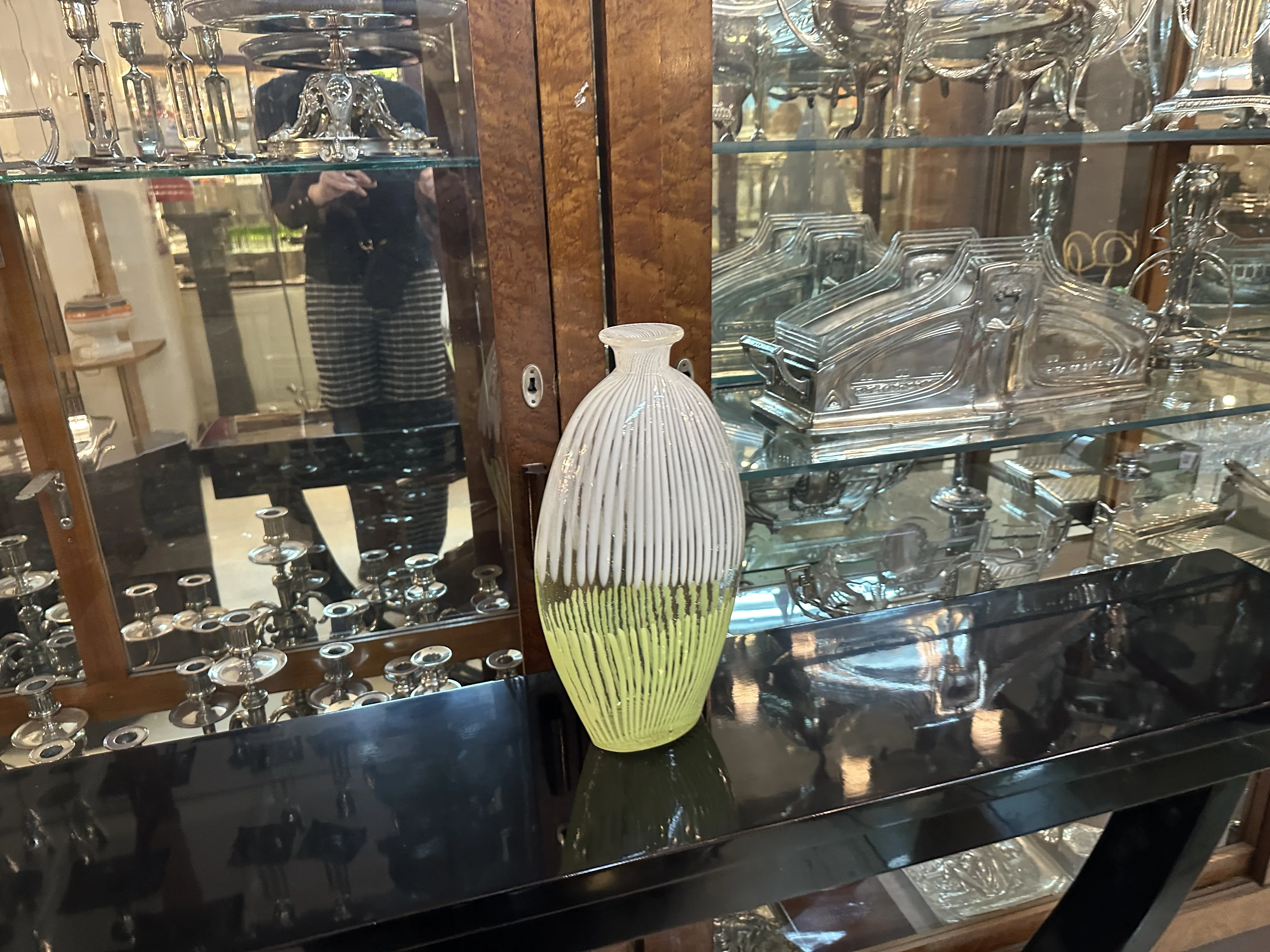 antico vaso di Murano con motivi giallo e bianco, ambientato tra oggetti in metallo e legno