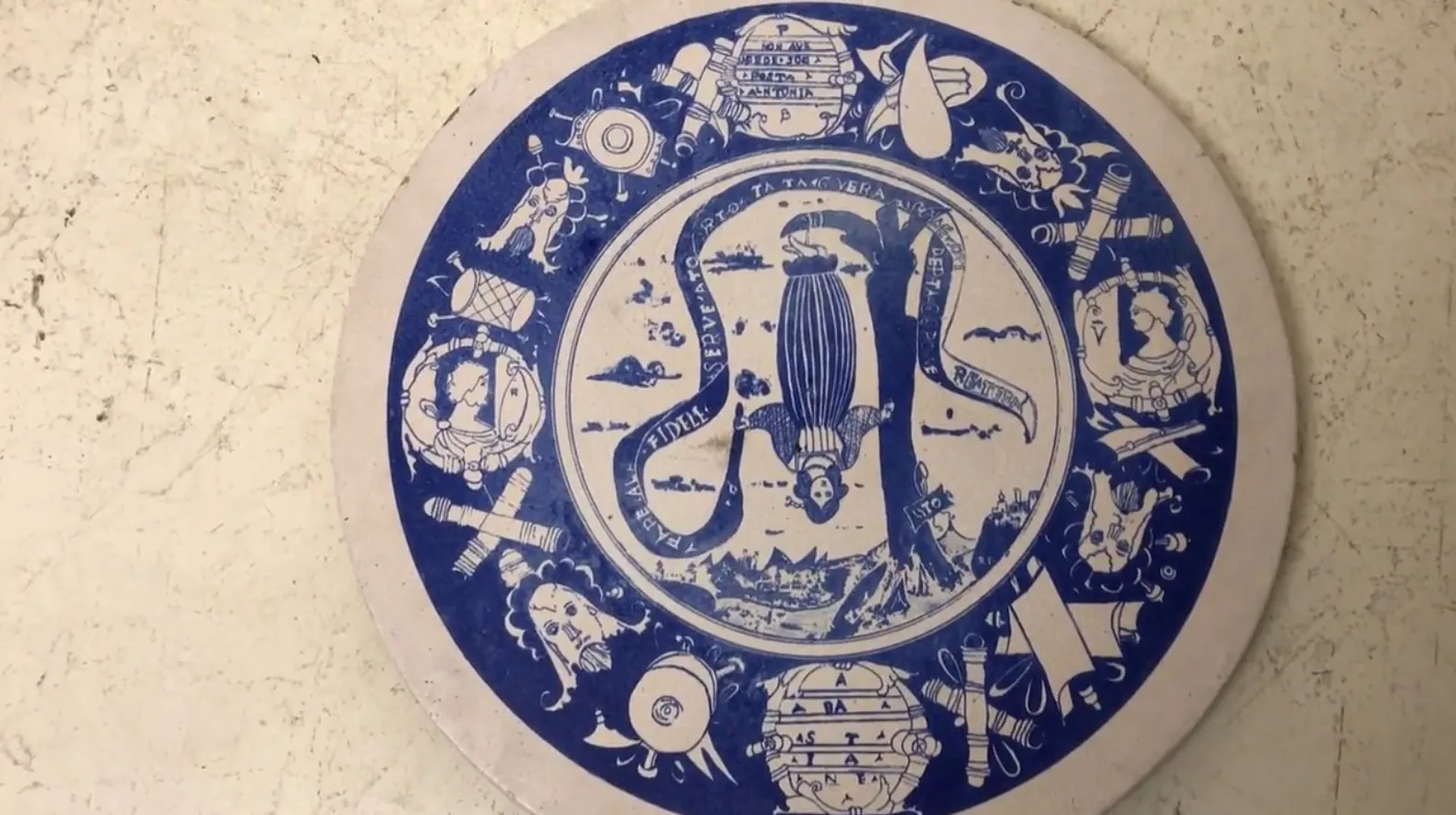 Plato de cerámica decorado con ilustraciones vintage en azul y blanco, muestra una figura central con un fondo marino.