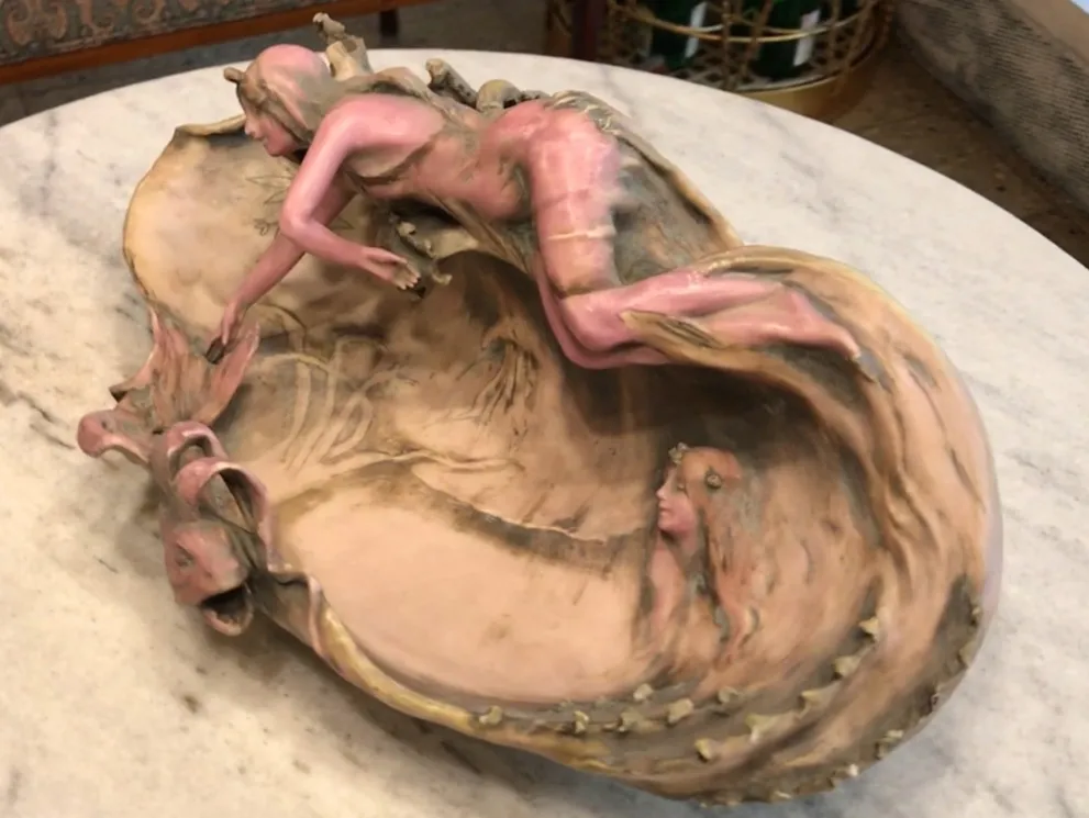 escultura de porcelana antigua con figuras femeninas en colores suaves sobre una base decorativa