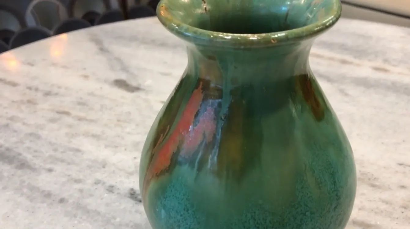 Vaso antiguo de cerámica en tonos verdes y anaranjados con detalles decorativos únicos