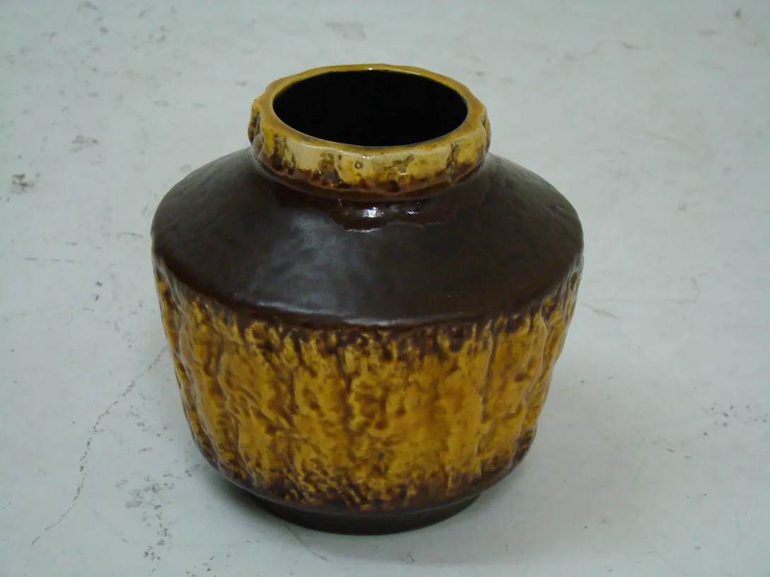 Antique ceramic jar with textured brown and yellow design.