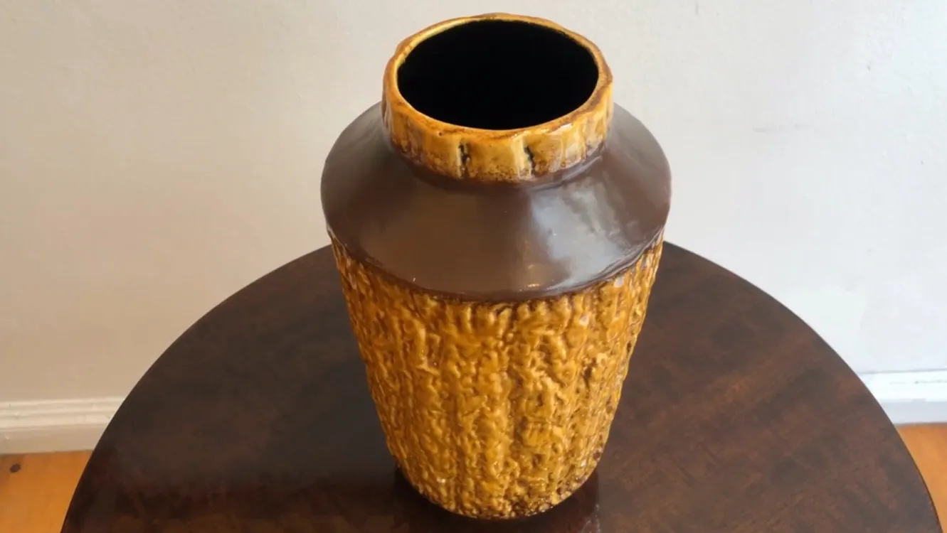 Vaso antigo de cerâmica em cor âmbar com textura rugosa.