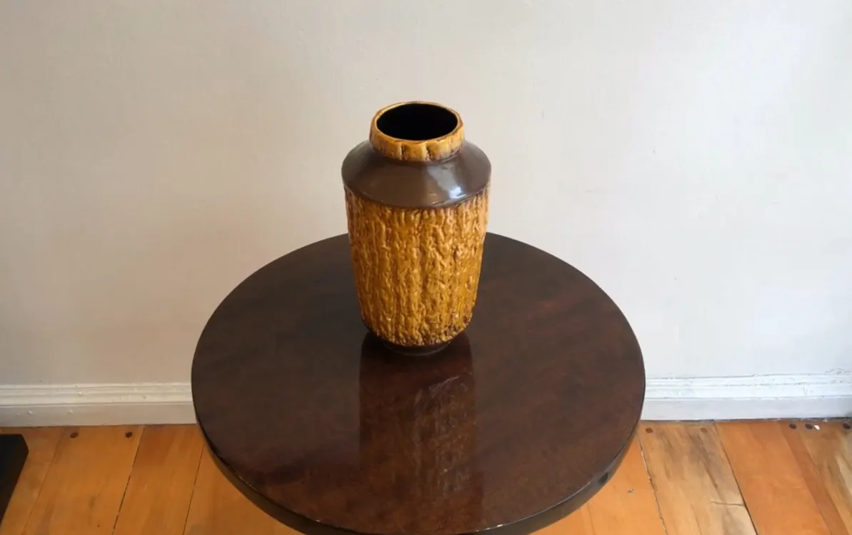 Antique ceramic vase in brown and yellow tones with a textured surface on a table