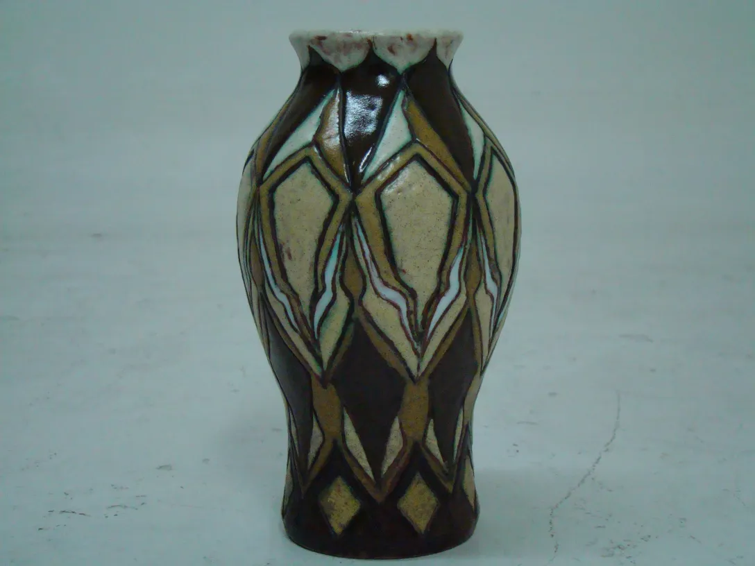 Antiga cerâmica decorativa com padrões geométricos em um fundo neutro.
