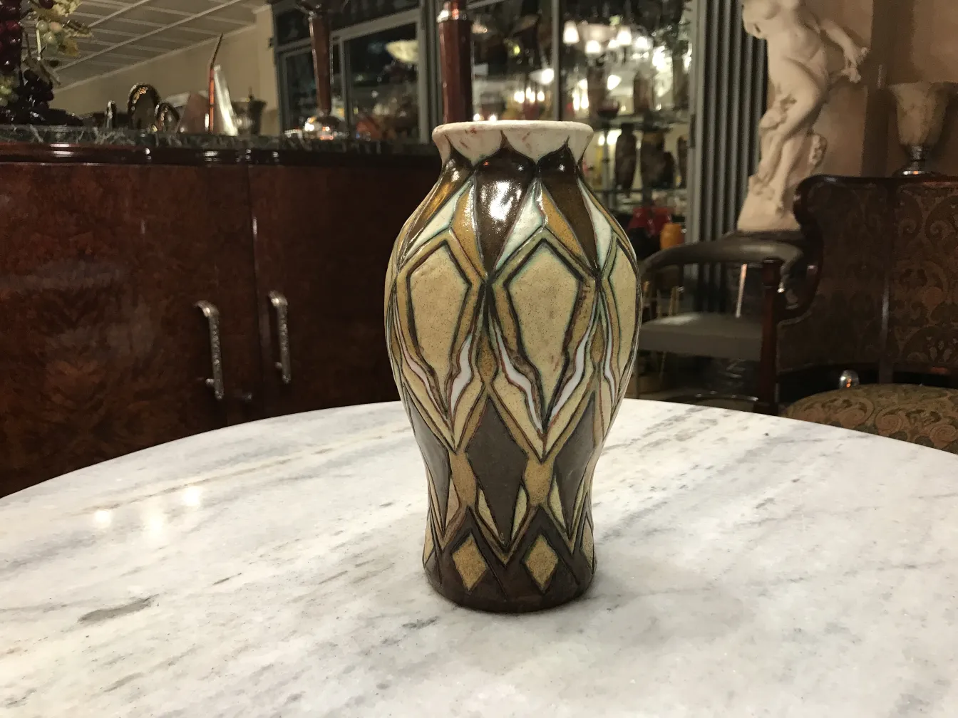 Vaso in ceramica antica con design decorativo in tonalità beige e marrone, su un tavolo.
