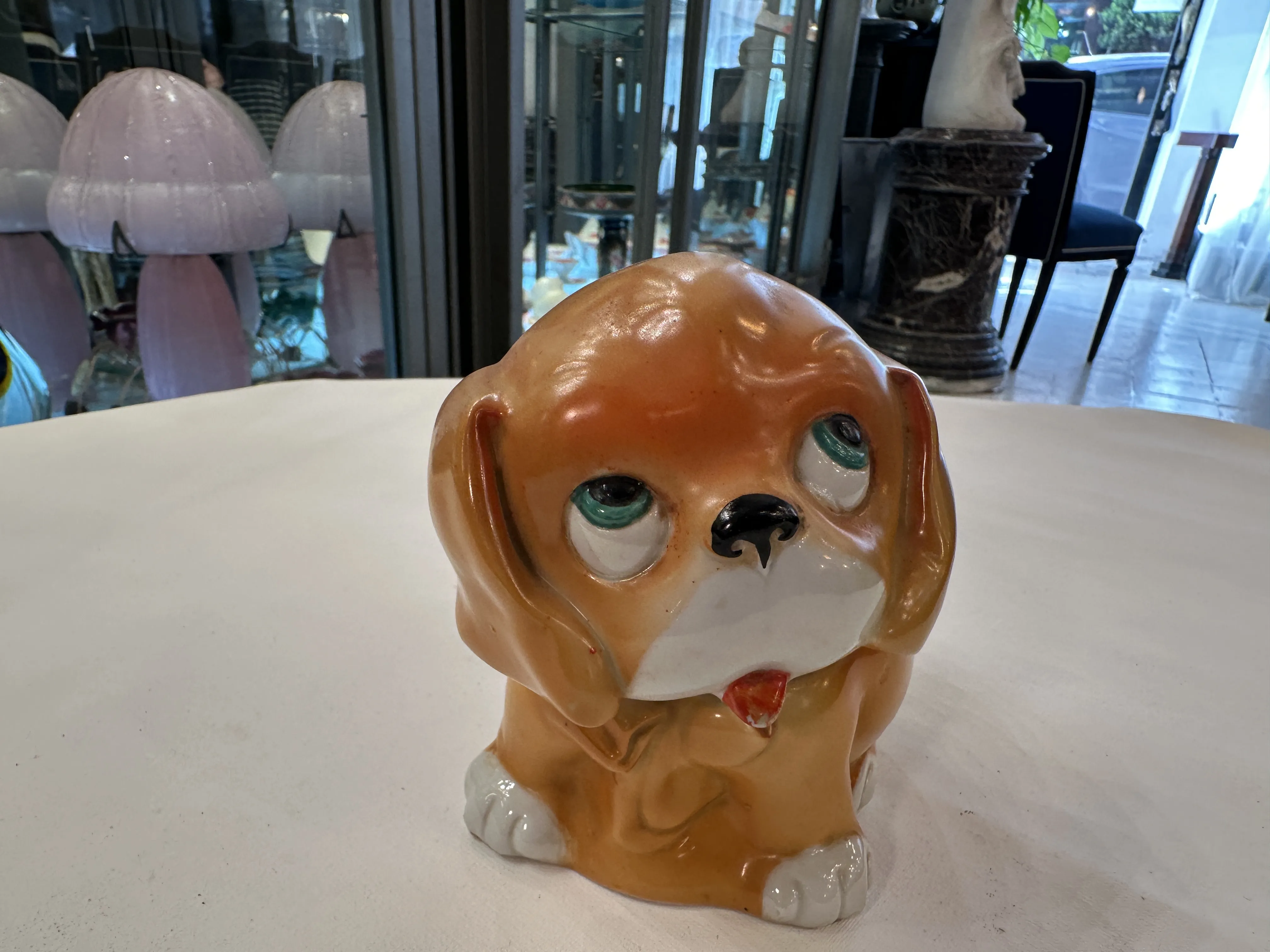 Cane in ceramica antica con occhi espressivi e colore marrone chiaro su un tavolo.