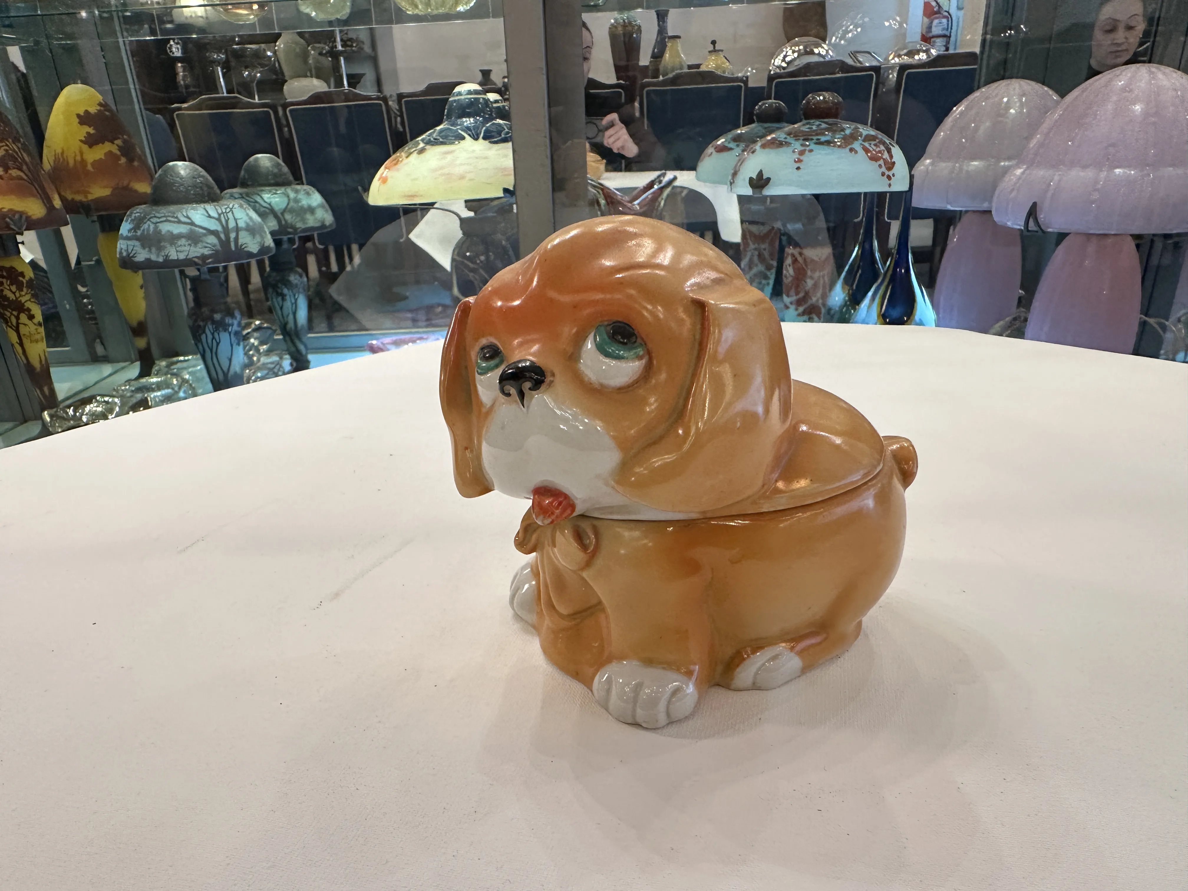 Antiga figurinha de cerâmica em forma de cachorro com detalhes coloridos, decorativa.