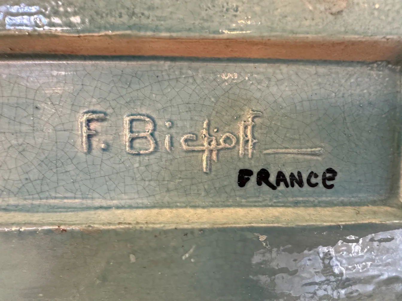 كائن سيراميك عتيق مع توقيع F. Bichoff وسياق زخرفي.