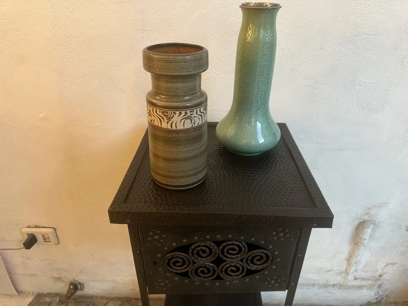 dos antiguos jarrones de cerámica de Sarreguemines, uno gris y otro verde, sobre una mesa.