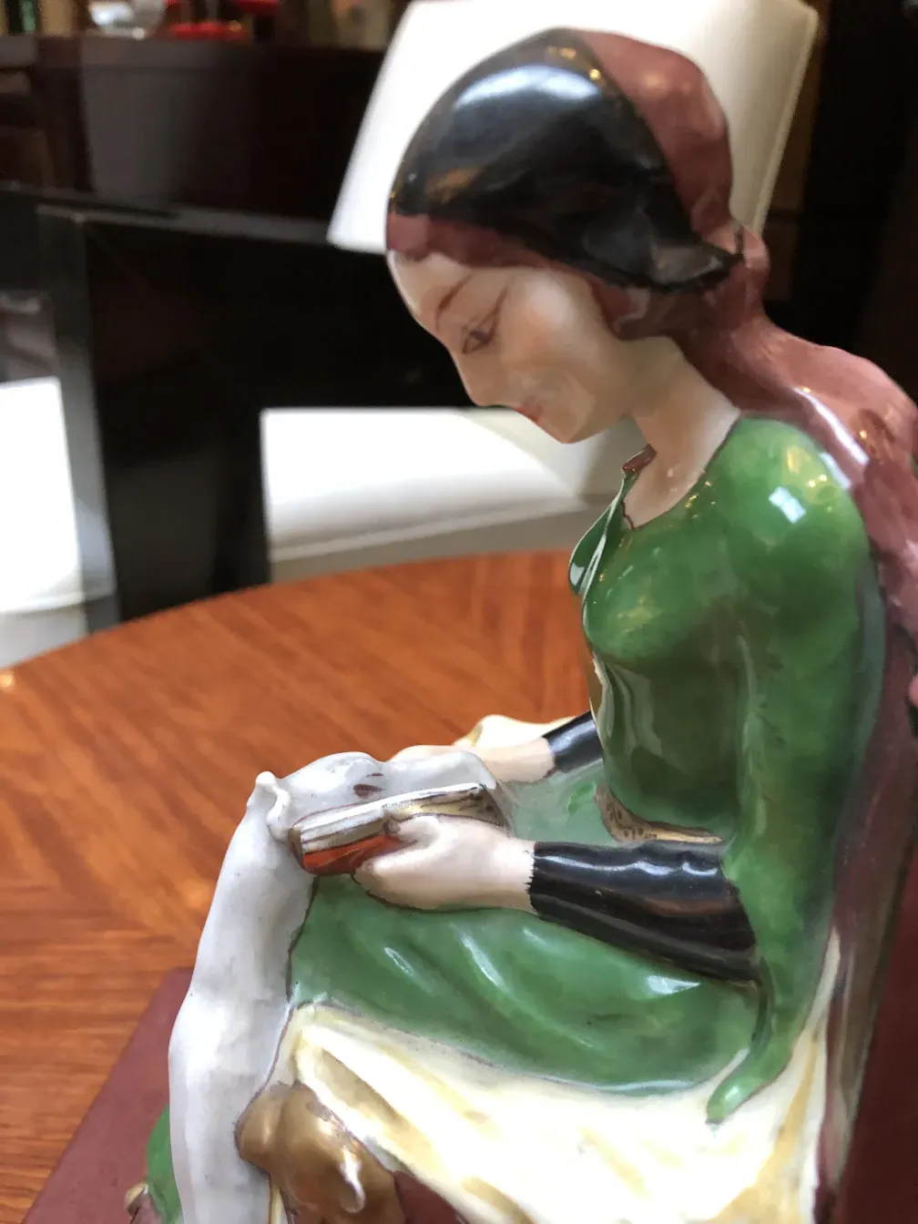 Antigua figura de mujer leyendo, acompañada de un perro, como aprieta libros.