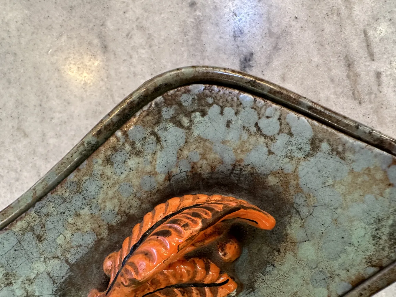 Ceramica antigua decorada con hojas en tonos naranja y marrón