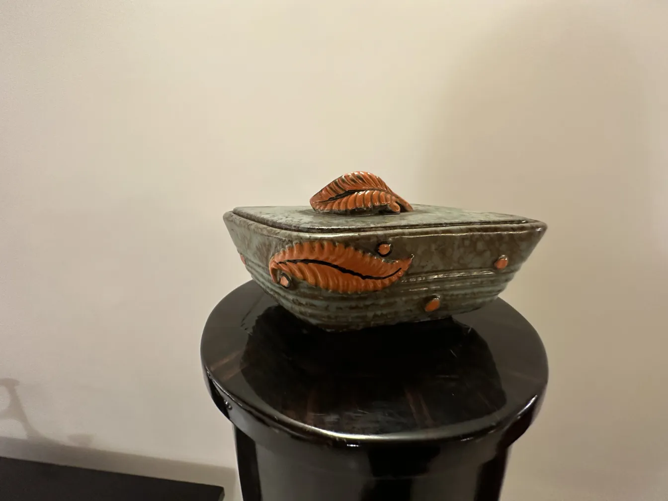 Ceramica antigua decorada con hojas en tonos naranja y marrón