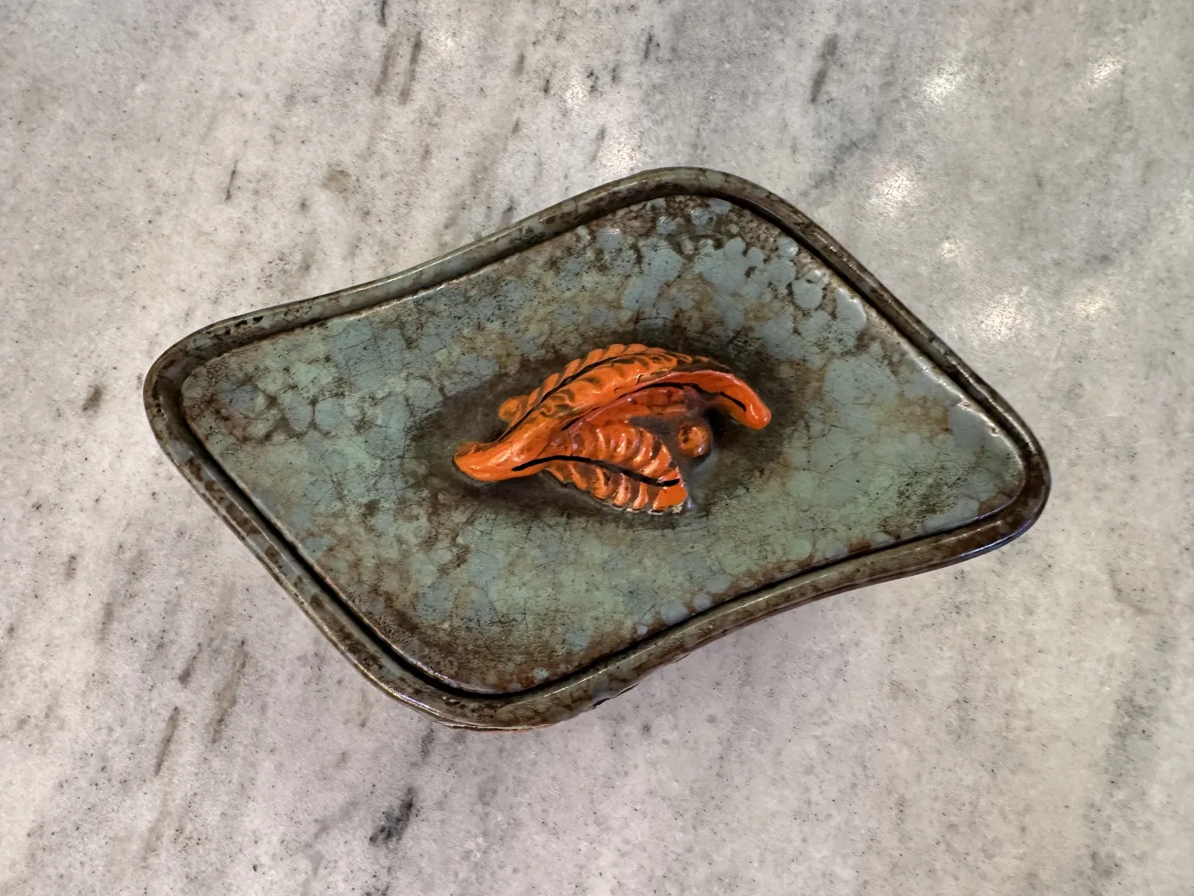 Antica ceramica decorata con foglie in tonalità di arancione e marrone
