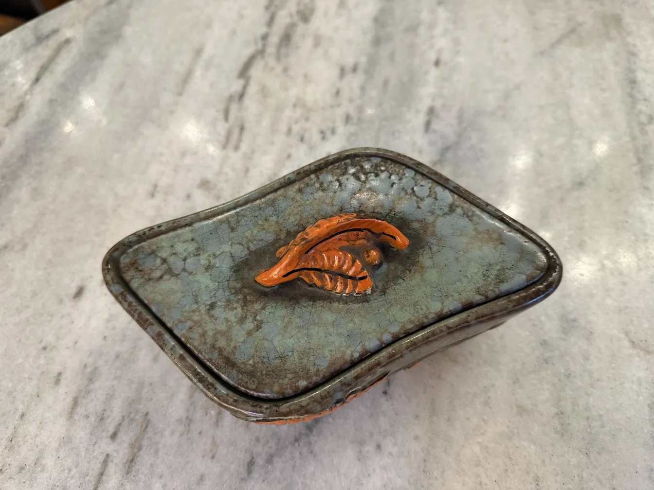 Ceramica antigua decorada con hojas en tonos naranja y marrón