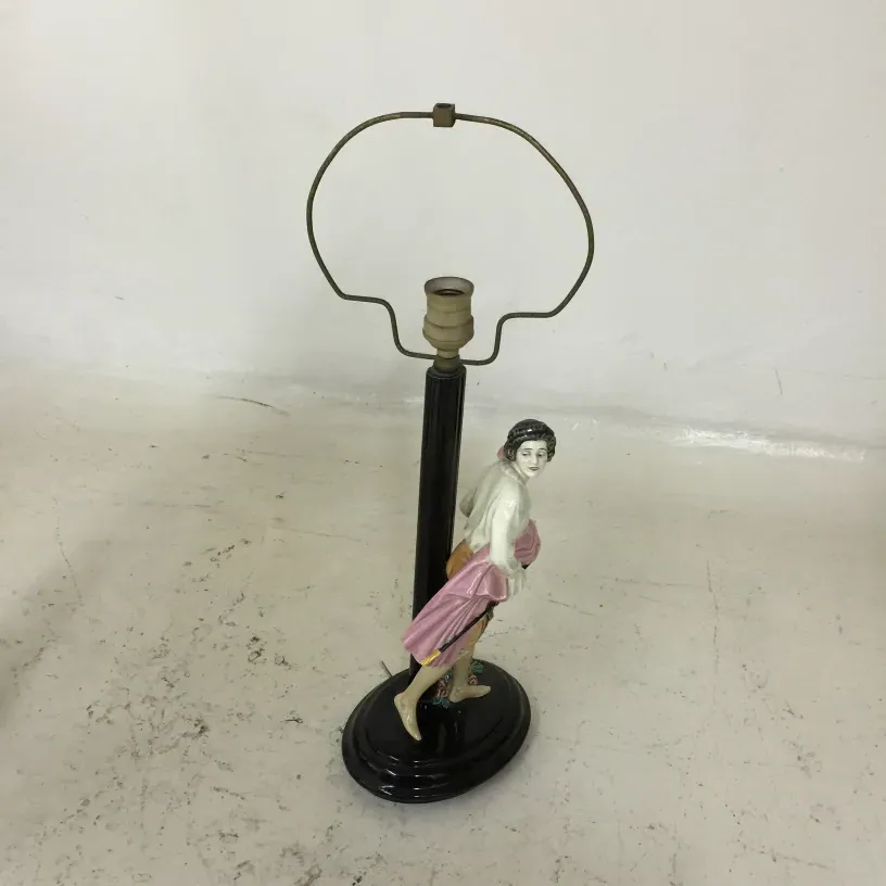 Antique table lamp featuring a decorative ceramic figure at the base, suitable for various settings.