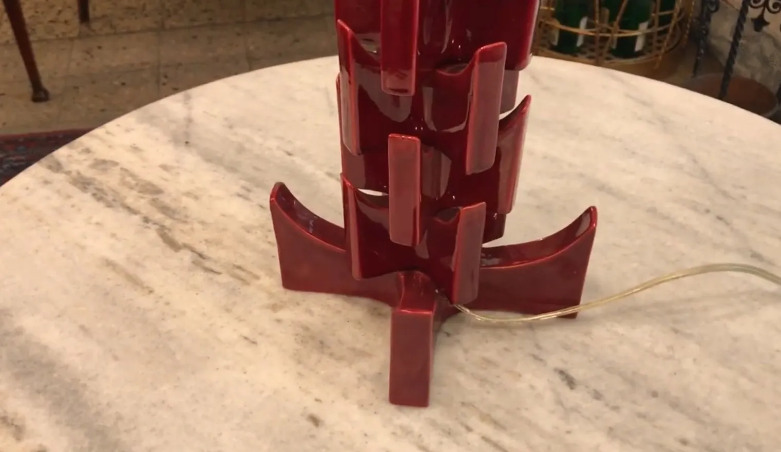 Lámpara de mesa antigua roja con un diseño único en una mesa de mármol.