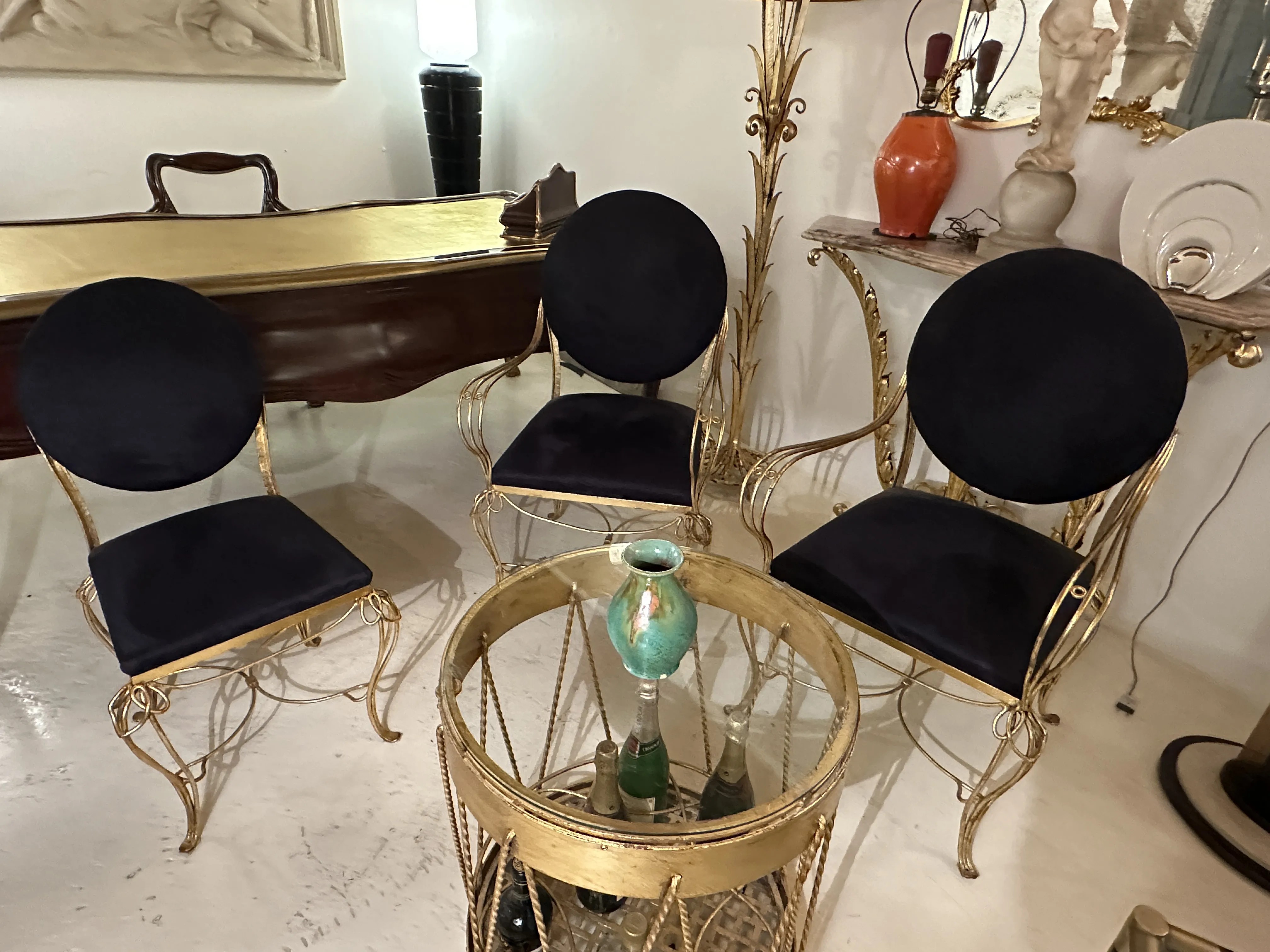 Three golden chairs with dark velvet cushions, ceramic table