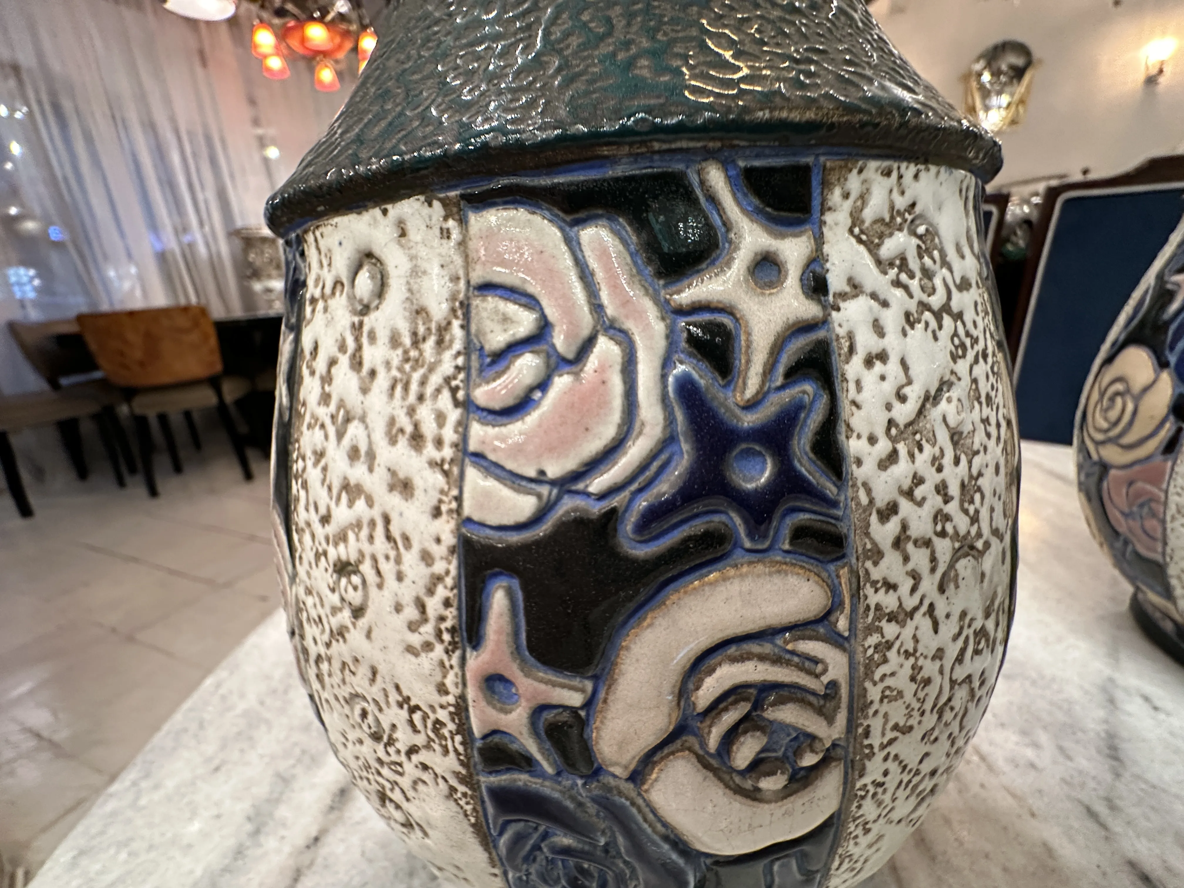 Antica ceramica a forma di amphora con decorazioni floreali colorate in un ambiente accogliente.