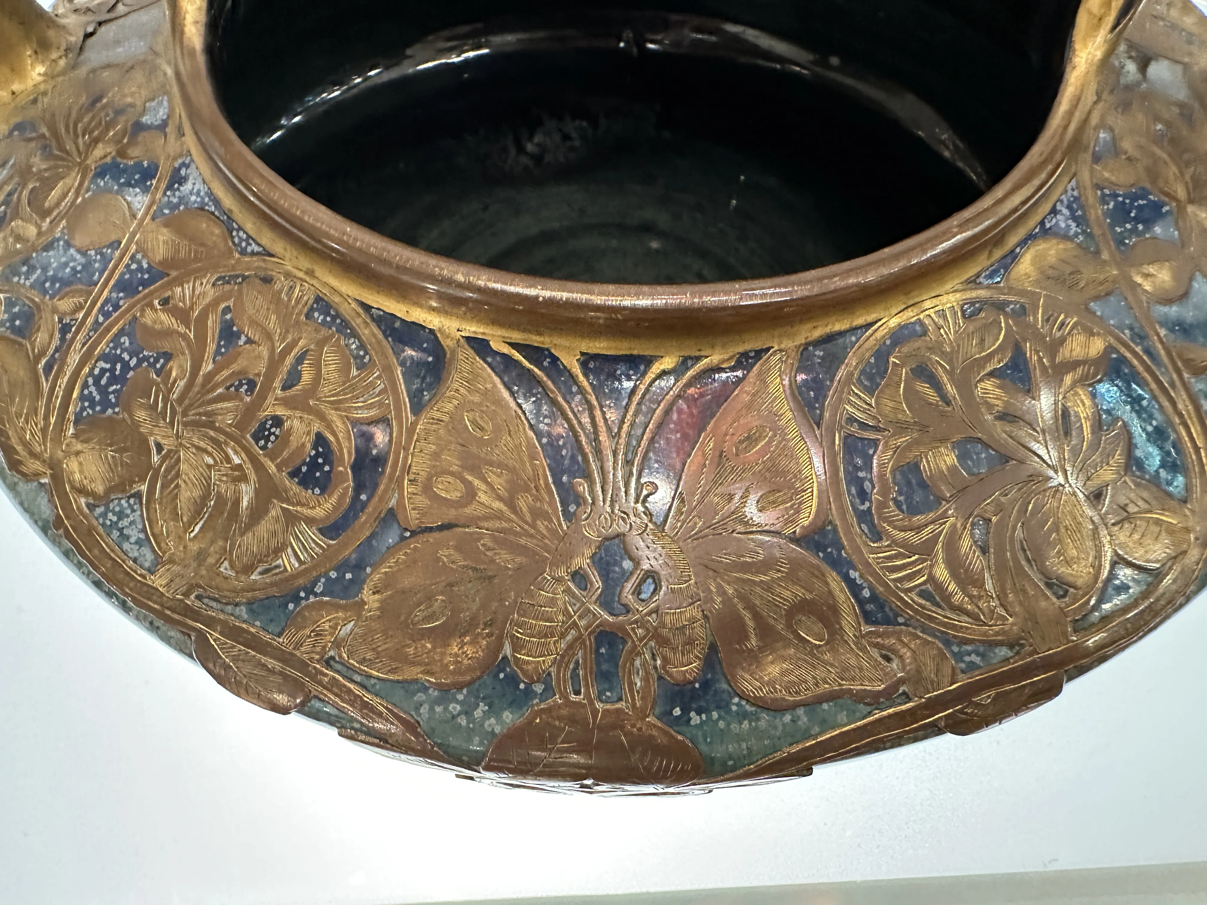 Antica ceramica con intricati disegni floreali e di farfalle, adornata in toni vivaci all'esterno.
