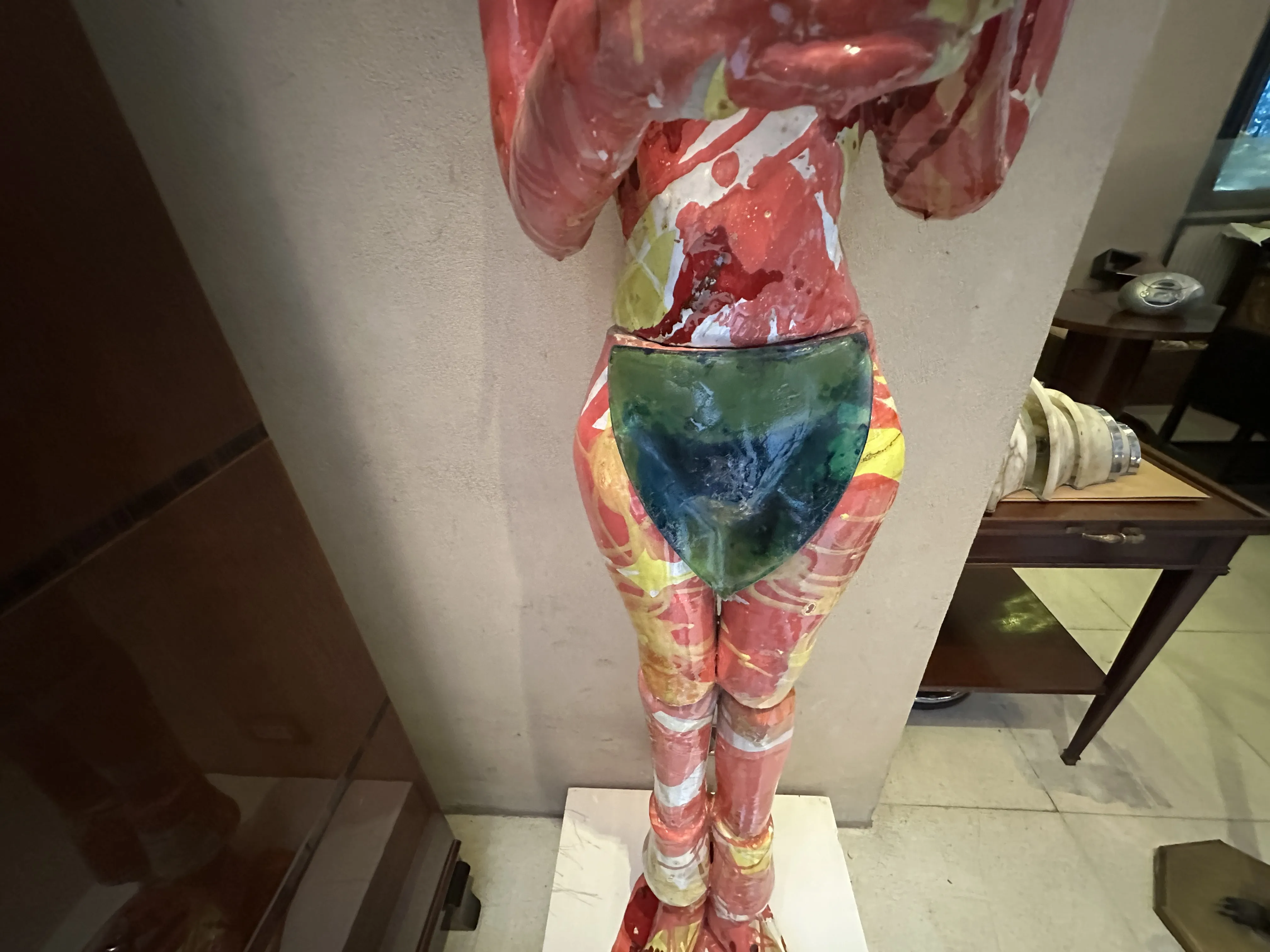 Figura di ceramica antica con colori vivaci e decorativi in un ambiente elegante.