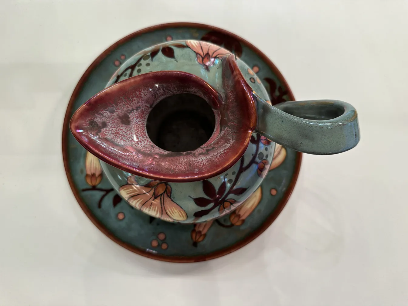 Tazza di ceramica antica con decorazione floreale colorata.