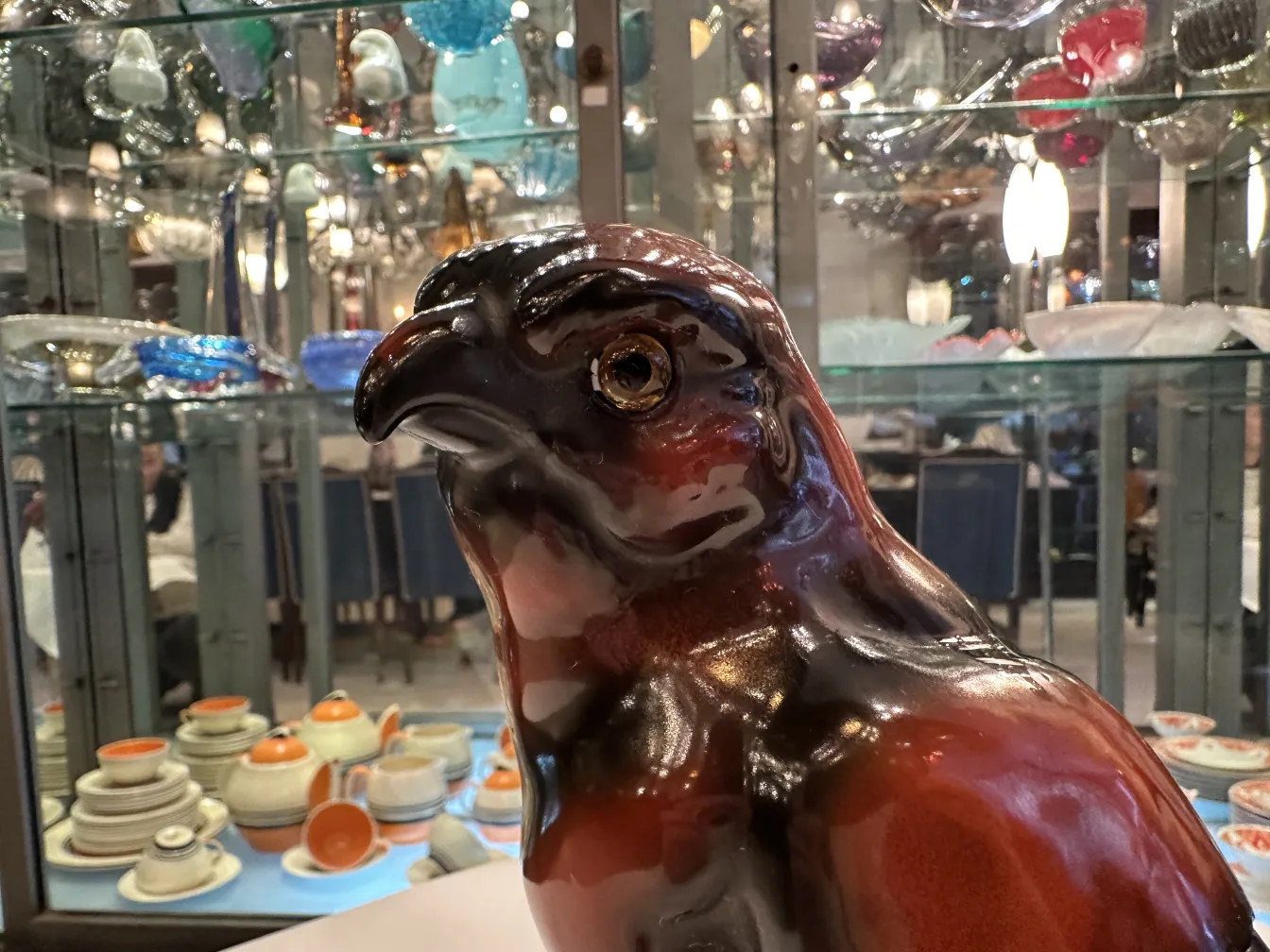 Figurine ancienne en céramique en forme d'oiseau, avec des détails brillants et expressifs.