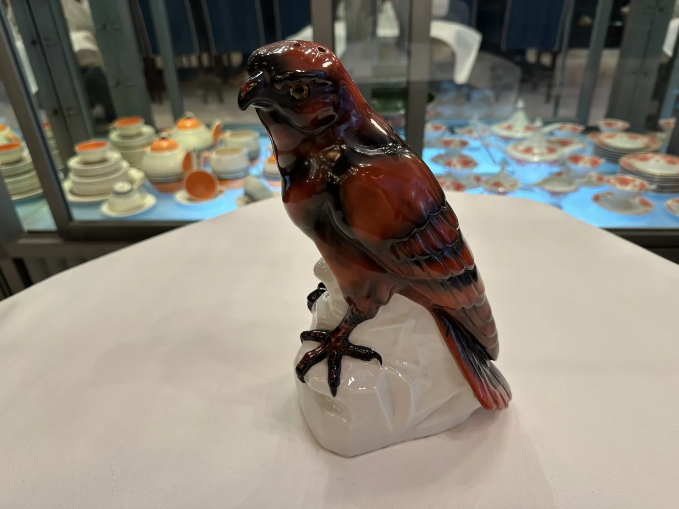 Figurinha antiga de cerâmica com formato de pássaro, com detalhes brilhantes e expressivos.