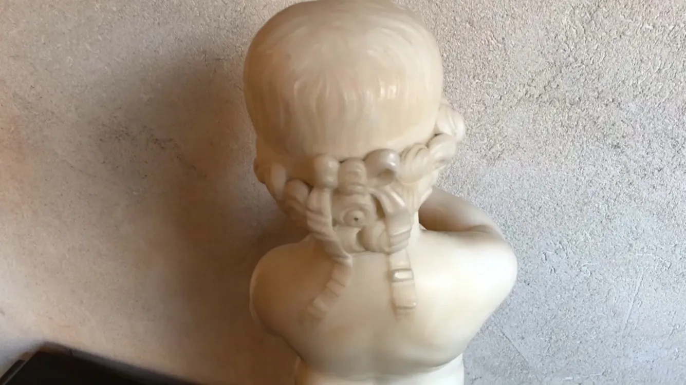 antique sculpture of a child holding a bird