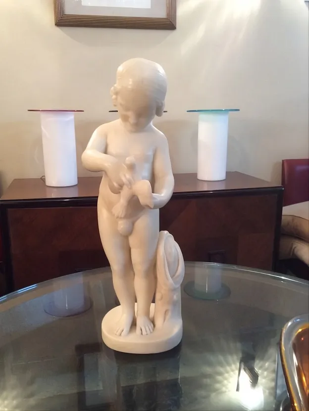 antique sculpture of a child holding a bird
