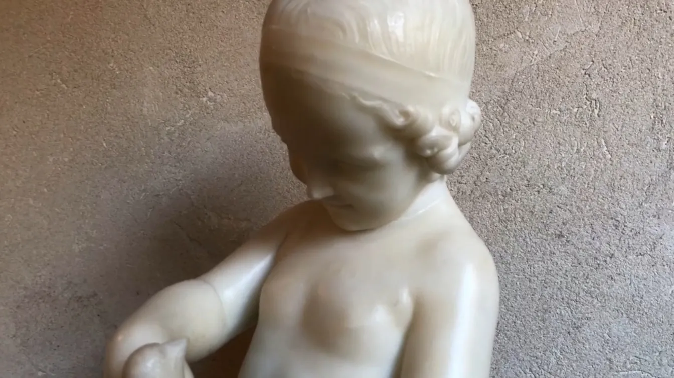 escultura antigua de un niño sosteniendo un pájaro